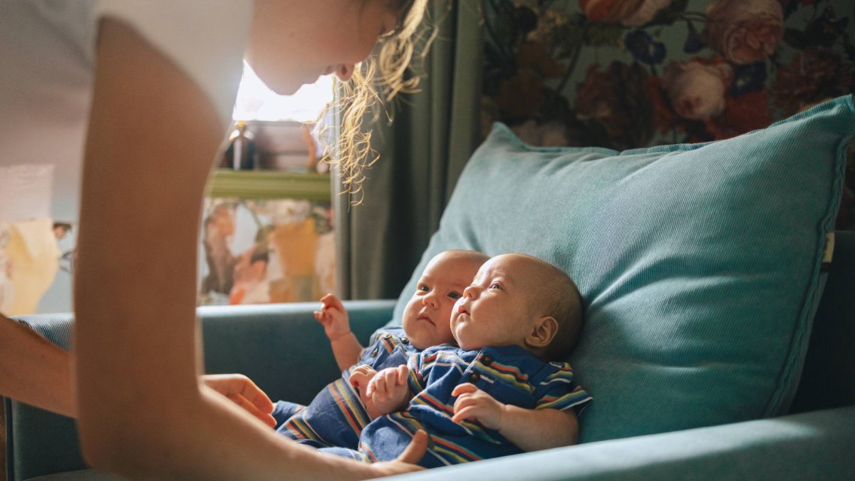 Una madre cuida a sus bebés gemelos en casa, una escena cotidiana que ilustra la realidad de las familias con partos múltiples