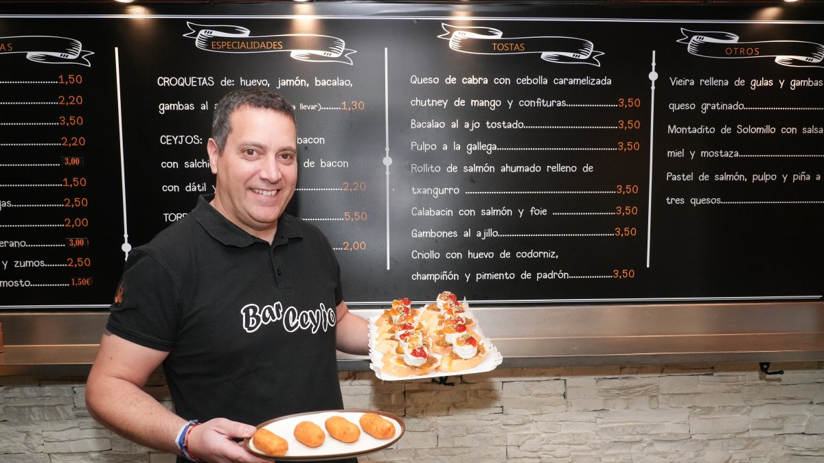 Alejandro Burgos muestra un plato con croquetas de huevo cocido y una bandeja con varias tapas de queso de cabra, mermelada y cebolla caramelizada.