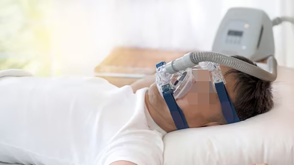Un hombre con un comprensor de aire utilizado por la Apnea del Sueño