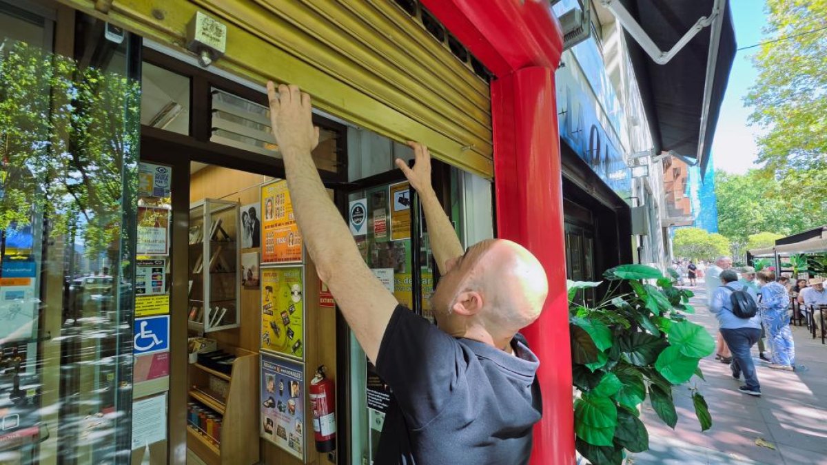 Imagen de archivo de un comerciante levantando la persiana de su negocio para comenzar la jornada de trabajo.