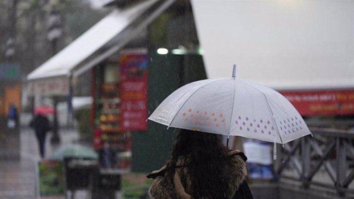 Una persona se protege de la lluvia en una imagen de archivo