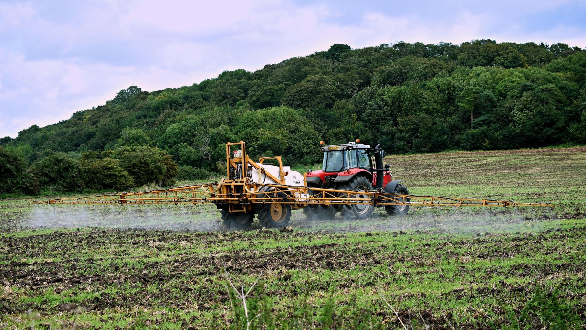 Un agricultor rocía un fertilizante en un campo de cultivo.