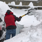Un hombre retira la gran cantidad de nieve acumulada en su vehículo estacionado en el Puerto de Pajares de León.- ICAL
