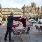 Un  trabajador extiende el mantel en la mesa de una terraza de la la plaza Mayor de Salamanca. ICAL