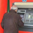 Una persona mayor utiliza un cajero automático en el exterior de una sucursal bancaria. EUROPA. PRESS