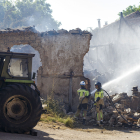 Los bomberos sofocan el fuego en una de las viviendas arrasadas por el incendio.- SANTI OTERO