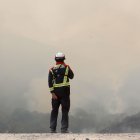 Varios bomberos observan el incendio forestal en La Baña, León