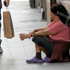 UNA PAREJA PASA JUNTO A UN POBRE QUE PIDE LIMOSNA CERCA DEL AYUNTAMIENTO DE VALLADOLID, EN LA IGLESÍA DE JESÚS NAZARENO. MENDICIDAD. POBREZA. HORIZONTAL