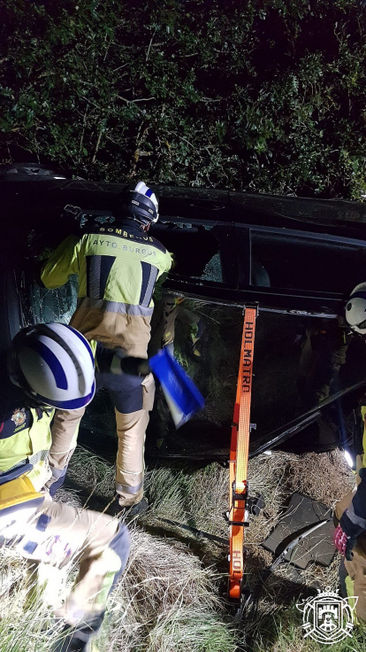 Los Bomberos de Burgos trabajan para sacar el coche del desnivel.