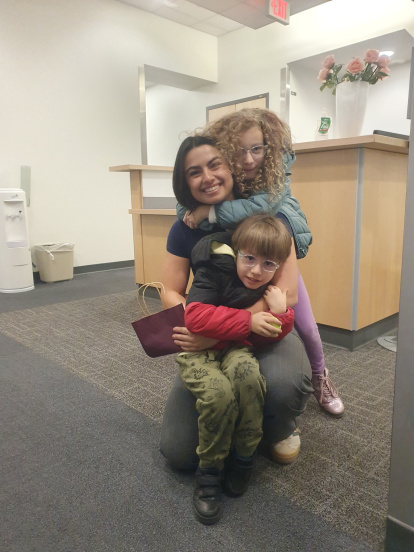 Los dos niños de la familia junto a Emily, la guía médica de la familia durante la primera visita a Boston.
